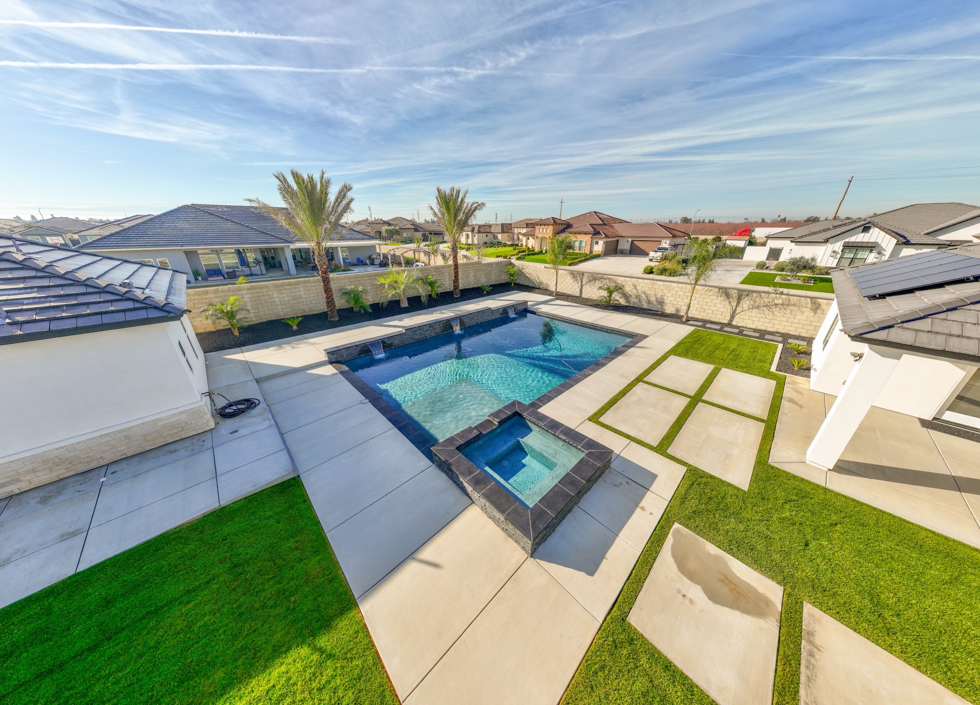 Aerial view of custom gunite pool with spa, stone features, and palms — Bakersfield, CA