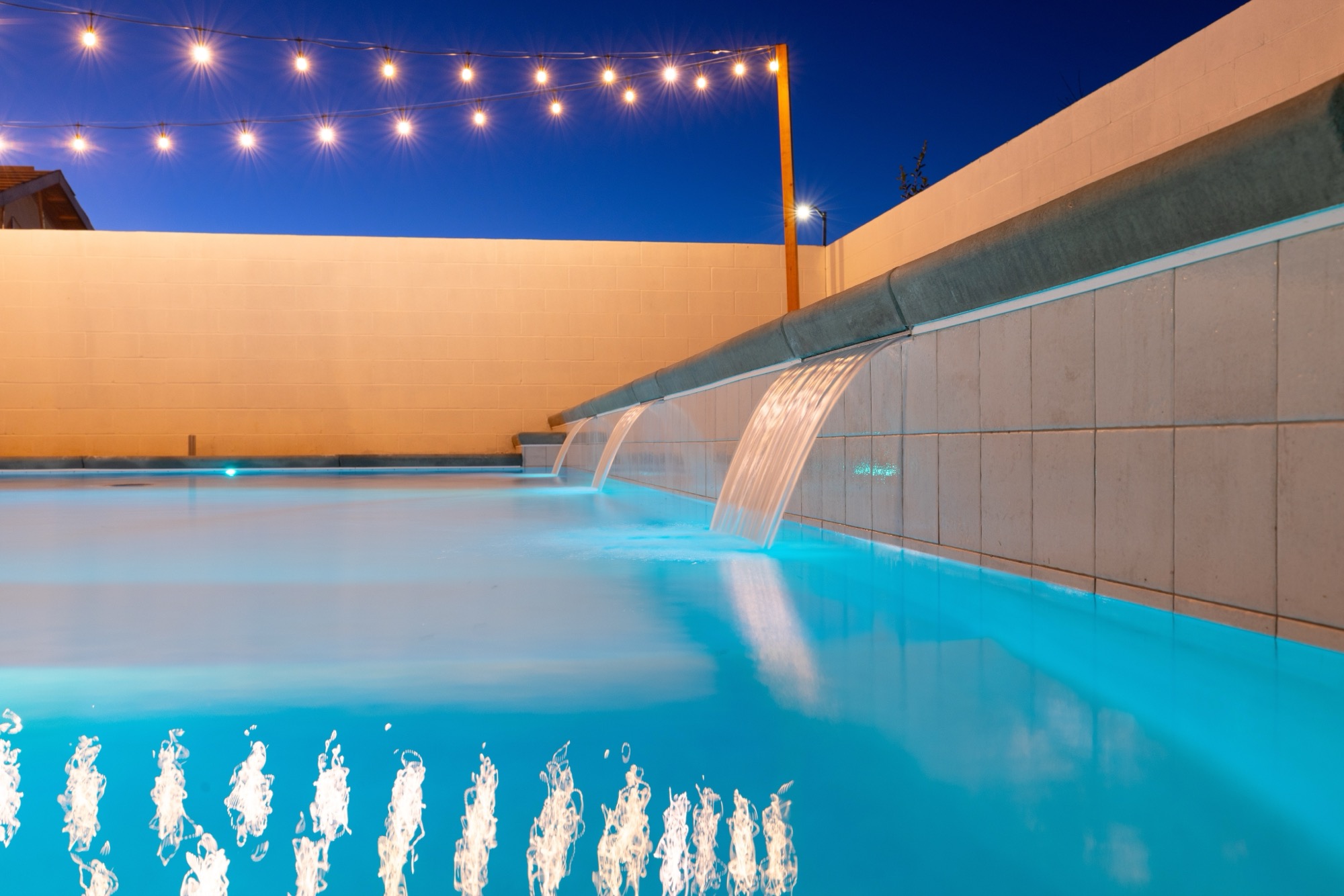 Custom gunite pool with waterfall and blue LED lighting at night — Bakersfield, CA