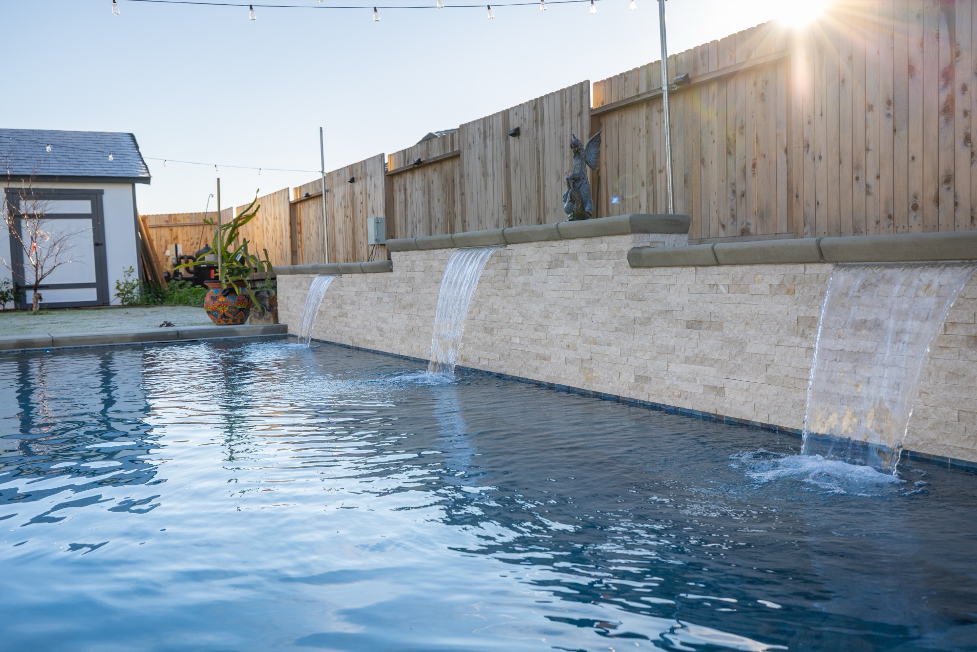 Custom gunite pool with stone sheer descents at sunset — Bakersfield, CA