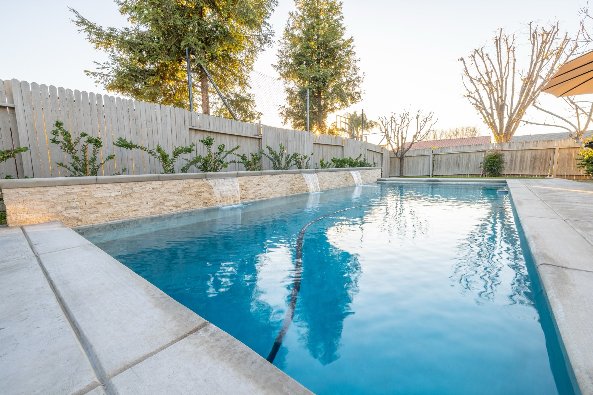 Custom gunite pool with stone wall and spillway at dusk